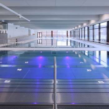 Modern indoor pool in Triesen with illuminated pool and large glass front.
