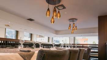 Modern restaurant area with a view of the window front and stylish hanging lamps.