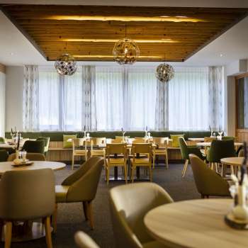 Another corner of the dining area, with the same round tables, a cozy atmosphere and modern lighting installations.