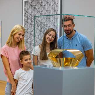 Family looking at a golden sculpture in the Liechtenstein Art Museum - art enjoyment for young and old in the heart of Vaduz.