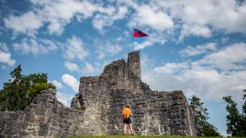 Hiker stands in front of the imposing ruins of Schellenberg Castle under a blue sky