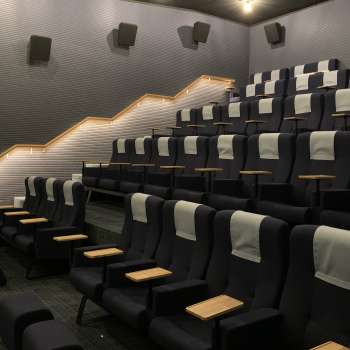 Modern movie theater in the Skino Schaan with comfortable seats, small tables and subdued lighting.