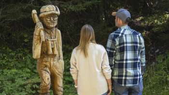 Walkers look at carved wooden figures along the Walser Saga Trail