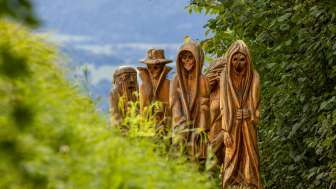 Wooden figures on the Walser legend trail in Triesenberg Detailed view of carved wooden figures in mystical depiction on the Walser Legend Trail in Triesenberg, surrounded by green nature