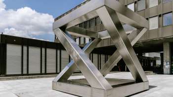 Geometric sculpture Z-Cube by Georg Malin in Vaduz - staggered stainless steel surfaces in the shape of a cube in a public square.