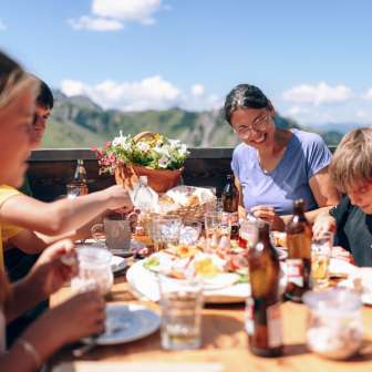 Family having lunch together on a sunny terrace in Sarreis, surrounded by mountains and regional specialties