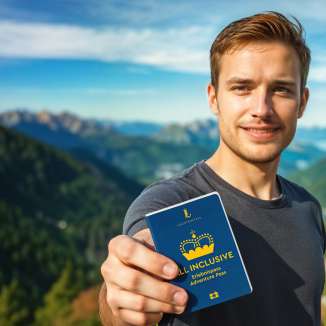Man shows the ALL INCLUSIVE Adventure Pass with mountain panorama in the background
