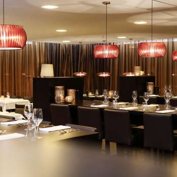 Stylish dining room with dark furniture, red designer lamps and elegant ambience