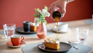 Hand pours caramel sauce over a dessert in the stylish RUUF restaurant at the b_smart Hotel Kloster Schaan in Liechtenstein