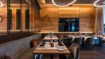 Modern restaurant area with fine wood furnishings, elegant tables and comfortable armchairs.