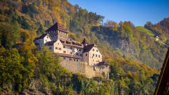 Vaduz Castle in Liechtenstein, surrounded by autumn-colored trees and sunny skies