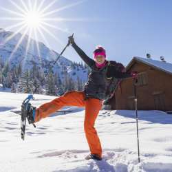 Cheerful snowshoe hiker enjoying the winter in Malbun, Liechtenstein, under a radiant sun.