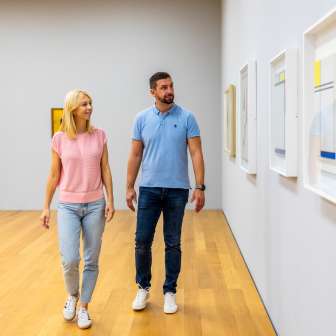 A couple strolls through the Liechtenstein Art Museum in Vaduz and looks at contemporary works of art on the wall.
