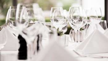 Close-up of several stacked wine glasses on a white table with luminous highlights.
