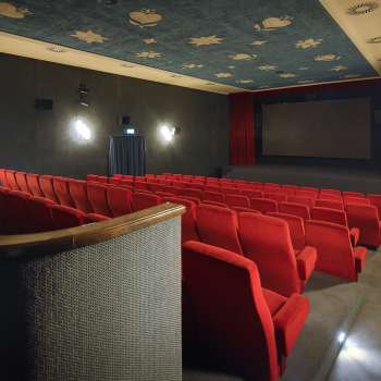 Side view of the cinema auditorium of the Altes Kino Vaduz with red armchairs and atmospheric lighting.
