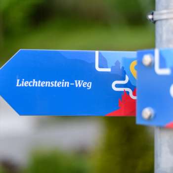 Blue signpost with the inscription "Liechtenstein Trail" in a modern design.
