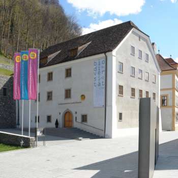 View of the Liechtenstein NationalMuseum in Vaduz with historic buildings and colorful flags