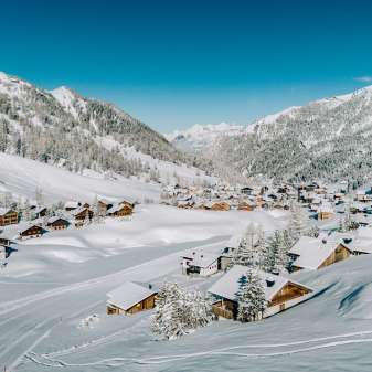 Aerial view of Malbun in winter with snow-covered wooden houses, nestled in the Liechtenstein Alpine landscape
