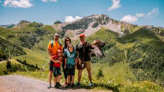 Family shoot with Adler in Malbun Family posing with an eagle in summer against the impressive mountain backdrop of Malbun in Liechtenstein.