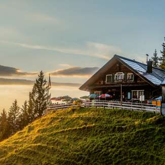 Gafadura hut on a green hill in Liechtenstein at sunset with a panoramic view over the mountains
