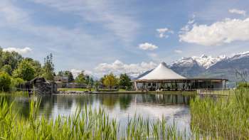 Modern pavilion on the water in the Grossabünt recreational park in Liechtenstein, surrounded by nature and with a view of the Alps.
