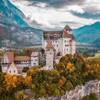 Panoramic shot of the medieval Gutenberg Castle in Liechtenstein with a colorful autumn landscape and Alpine backdrop