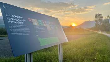 Information board on the Vaduz food field with a view of the Alps at sunset - a place of learning about sustainable nutrition in Liechtenstein.