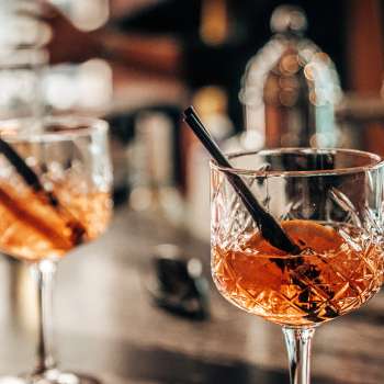Two aperitif glasses with orange slices on the bar