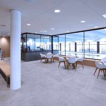 Bright seating area in the Triesen indoor pool with a view of the pool through the glass front.