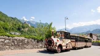 Citytrain passes through Vaduz, in the background Vaduz Castle and the Alps in bright sunshine