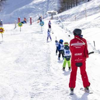 Ski instructor accompanies children on the practice lift in Malbun - ideal ski area for families and beginners in Liechtenstein.