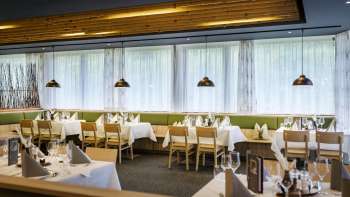 An inviting dining area with round tables and soft green chairs, furnished in a modern, natural style.