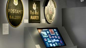 Museum room with old post signs and a digital display on the history of the post office in Liechtenstein.