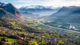 Sweeping views from the hillside over the Rhine Valley with fields, villages and snow-capped mountains - a natural idyll in Liechtenstein