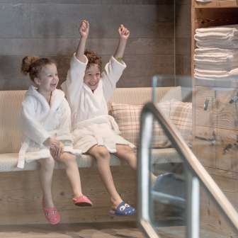 Two children in bathrobes enjoy the wellness area at the Hotel Gorfion - family vacation with a feel-good factor in Malbun.