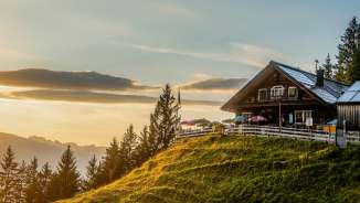 Gafadura hut on a green hill in Liechtenstein at sunset with a panoramic view over the mountains