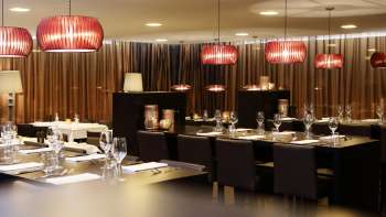 Stylish dining room with dark furniture, red designer lamps and elegant ambience