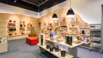Bright visitor center with modern wooden shelves filled with souvenirs, specialties and information material. Bright visitor center with modern wooden shelves filled with souvenirs, specialties and information material.