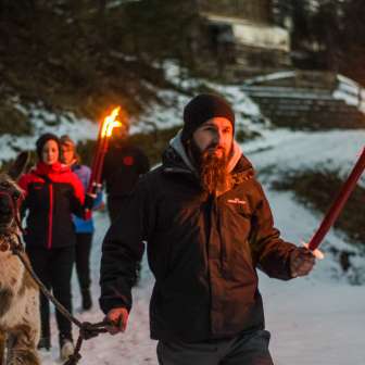 Group on a guided llama hike in snowy Liechtenstein with torches - atmospheric outdoor adventure for young and old.
