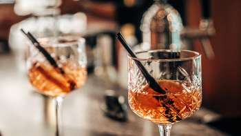 Two aperitif glasses with orange slices on the bar