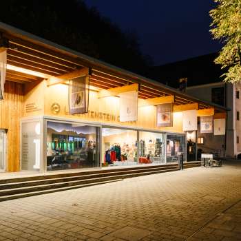 Modern visitor center with glass front in Vaduz at night, invitingly illuminated.