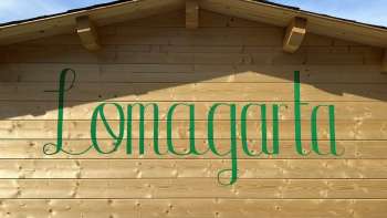 View of the green Lömagarta logo, which is stylishly emblazoned on the wooden façade of the cozy beer garden.
