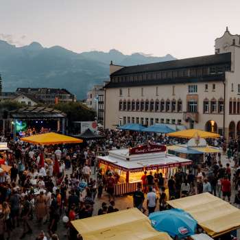 The Vaduz Town Hall at dusk with fairy lights, children playing on a table tennis table and a summery atmosphere on the national holiday