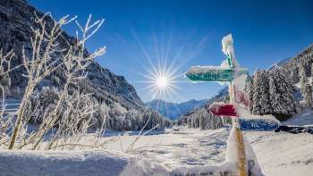 Snow-covered signpost in the Valüna cross-country skiing area - Steg with radiant winter sunshine