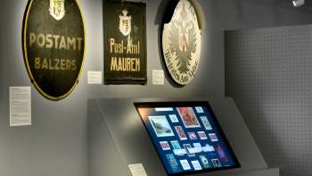 Museum room with old post signs and a digital display on the history of the post office in Liechtenstein.