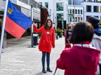 City guide presents the Liechtenstein flag during a guided tour through the center of Vaduz