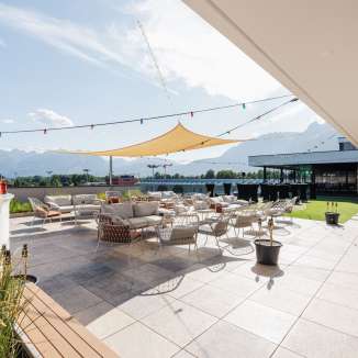 Spacious terrace with lounge furniture and awning at Hotel kommod in Ruggell - the perfect place to relax with a view of the mountains.