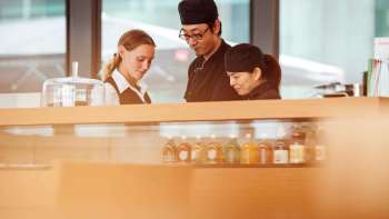 Three employees of the café in the Liechtenstein Art Museum, working together at the counter and exchanging ideas.