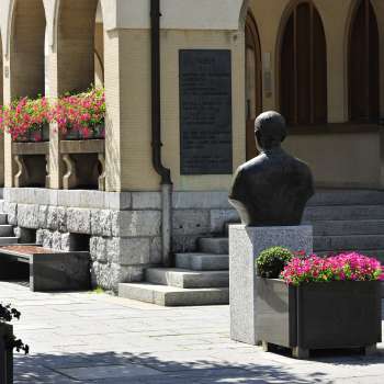 View of the entrance area of Vaduz Town Hall with flower arrangements, historical bust and wide stone steps - a cultural landmark in the center of Vaduz.