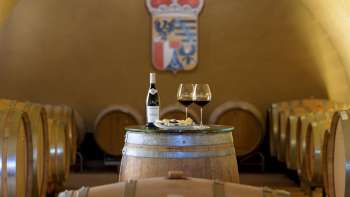 Atmospheric wine tasting in the wine cellar of the Princely Winery with two glasses and a bottle of red wine on a wooden barrel.